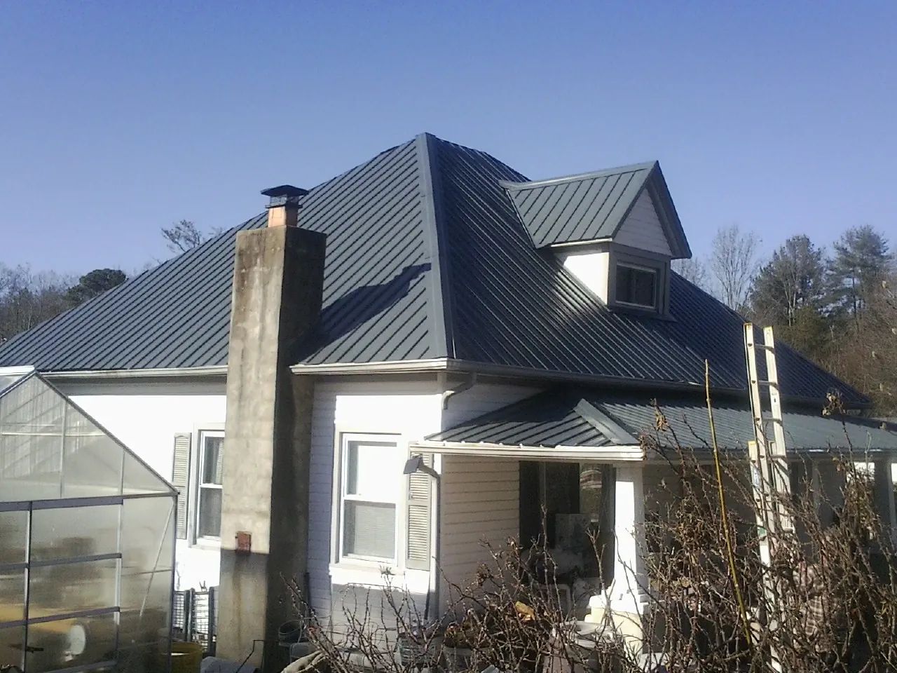 Dark blue standing seam metal roof on a white farmhouse with dormer — Slate & Tile Roof Repair by Roofing Brothers in Belvidere