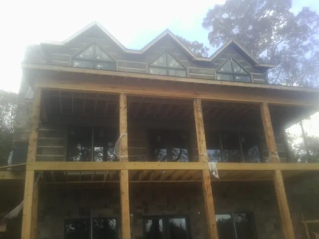 Dormers and porch framing on a large log home under construction — Roof Coating work by our crew in Belvidere